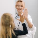 Young woman doctor pediatrician talking to little girl patient